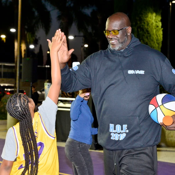 Shaquille O'Neil and a young girl doing a high-five on the Los Angeles Comebaq Court.